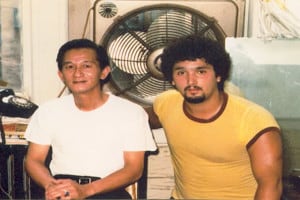 Grandmaster Leung on left with white t-shirt and younger James Cama in yellow shirt with his arm around his masters shoulder both looking at camera in a vintage 80's picture.